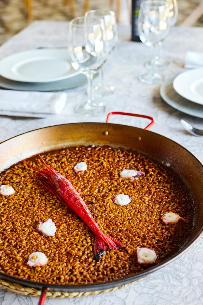 Paella de fondo de marisco con gamba en el centro sobre mesa con mantel blanco